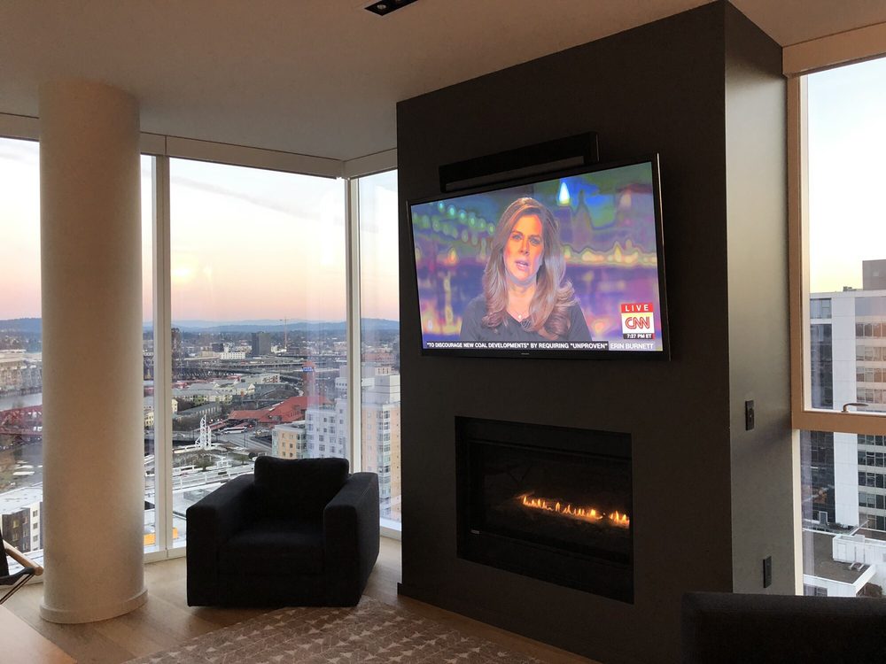 A TV mounted above a fireplace playing the news